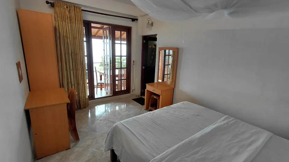 Bed and balcony doors in the Super Deluxe Double Room at The Mist.