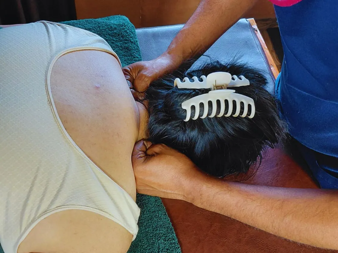 Hands massaging a guest's neck and shoulder area.